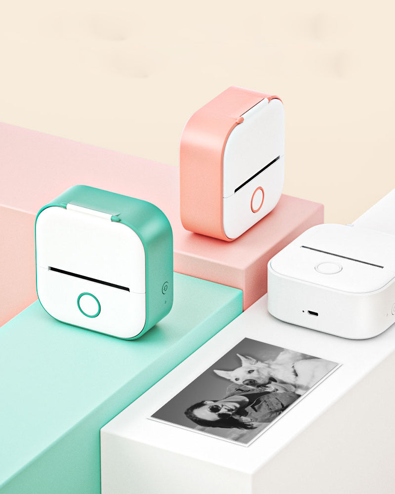 Two small printer devices on colorful platforms with a printed photo of a dog and person.